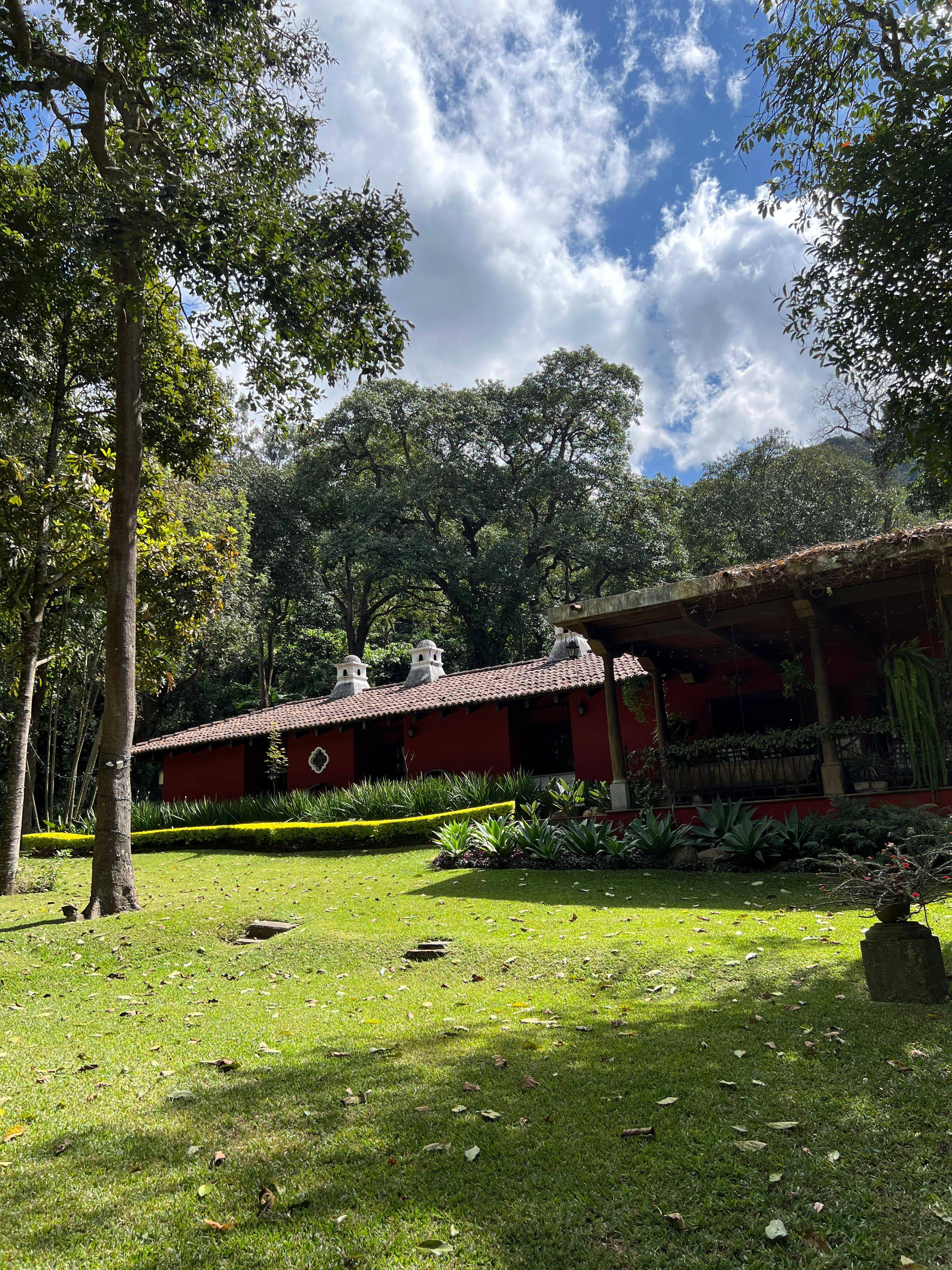 Jardín y casa histórica de Finca San Juan, rodeados de árboles en Antigua Guatemala.